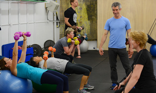 Adam Fawcett working with a group of clients participating in fitness classes using dumbbells and other dynamic approaches for functional fitness.